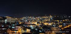 the city lights shine brightly in the night sky over some small town buildings and hills