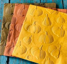 three place mats with pumpkins on them sitting next to each other in front of a blue wooden table