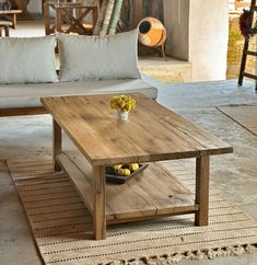 a wooden table sitting on top of a rug next to a couch and coffee table