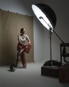 a woman sitting on a stool in front of a light