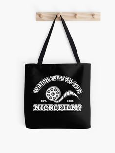 Black tote bag with varsity style text saying Which Way to the Microfilm? and clip-art of a microfilm reel Hidden Gems, Gems