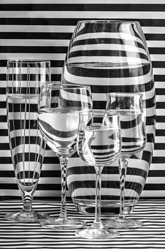 black and white photograph of wine glasses in front of a striped wall with vertical stripes