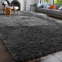 a living room with a couch, chair and rug on the floor in front of a fire place