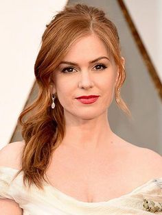 a woman with red hair wearing a white dress posing for the camera at an oscars event