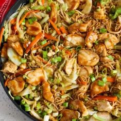 a skillet filled with noodles, chicken and veggies on top of a table