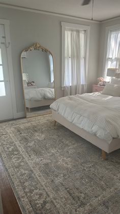 a bedroom with a large bed and a mirror on the wall in front of it