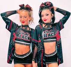 two women in black and red outfits posing for the camera with their hands on their head