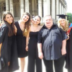 a group of people in graduation gowns posing for a photo outside an old building