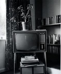 an old television sitting on top of a table next to a book shelf filled with books