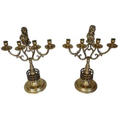 two brass candelabra candlesticks with figurines on each candle holder