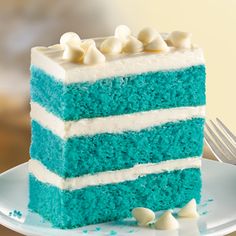 a piece of blue cake with white frosting on a plate next to a fork