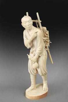 a carved ivory figure of a man carrying a cross and holding a baby in his arms