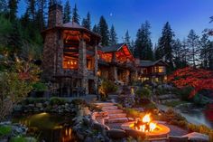 a fire pit is lit in front of a large log home with stone steps leading up to it