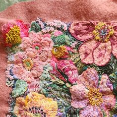 a close up of a pink blanket with flowers and leaves on the bottom half of it