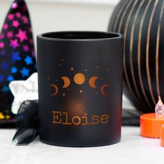 a black coffee mug with the word eloise written on it next to halloween decorations