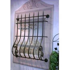 an old window with wrought iron bars on the front and sides, hanging in a white wall