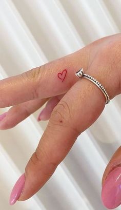 a woman's hand with a small heart tattoo on her left thumb and finger