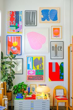 a living room filled with lots of art on the wall next to a table and chair