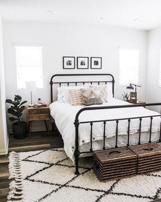 a bedroom with white walls and black iron bed frame, wicker baskets on the floor