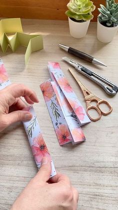 a person is making some paper flowers on a table with scissors and other crafting supplies