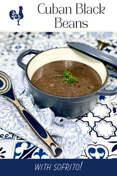 a bowl of black beans is sitting on a blue and white tablecloth with spoons