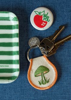 a green and white striped tray with two buttons, a keychain and a button on it