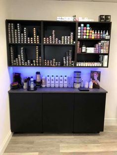 a counter with lots of bottles and containers on it in front of a white wall