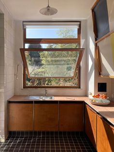 a kitchen with wooden cabinets and tile flooring next to a window that looks out onto the outdoors