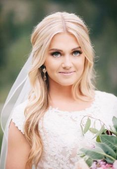 a woman in a wedding dress holding a bouquet and looking at the camera with a smile on her face