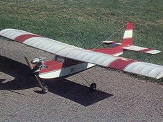 a small red and white airplane sitting on top of a field