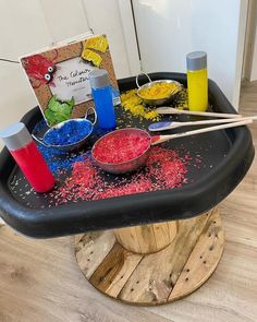 the table is covered with different colored powders and paintbrushes, along with two books