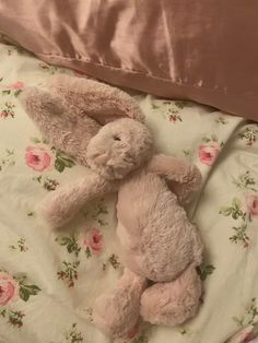 a pink stuffed animal laying on top of a bed next to a pillow and blanket