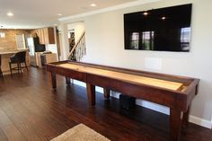 a flat screen tv mounted on the wall above a shuffle table in a living room