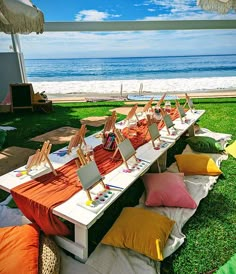 a row of chairs sitting on top of a lush green field next to the ocean