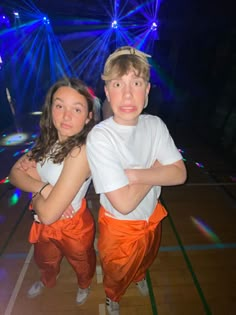 two young people posing for a photo in front of bright lights