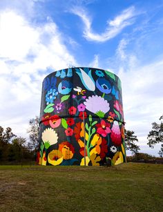 a large round building with flowers painted on it's side and blue sky in the background