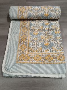 a blue and yellow blanket laying on top of a wooden floor next to a rug