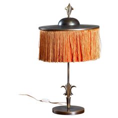 a lamp that is sitting on top of a wooden base and has fringed shade