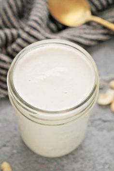 a glass jar filled with yogurt sitting on top of a counter next to a spoon