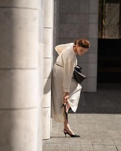 a woman leaning against a wall with her foot on the ground