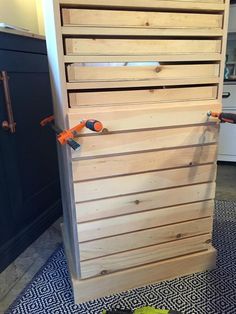 a wooden cabinet sitting on top of a kitchen floor next to a bowl of fruit