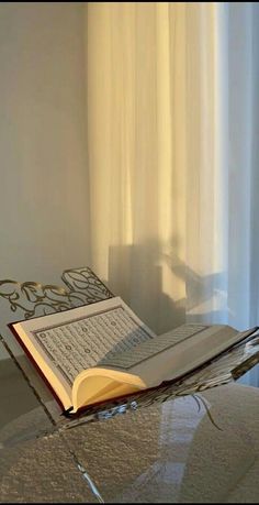 an open book sitting on top of a glass table