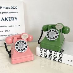 two old fashioned telephones sitting next to each other on top of a white table