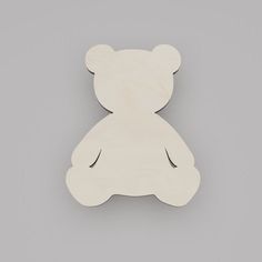 a wooden cutout of a teddy bear on a gray background, with the shape of a face