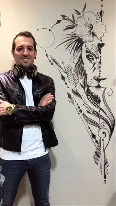 a man wearing headphones standing in front of a wall with a drawing on it