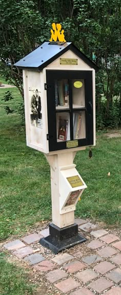 a mailbox with a book shelf built into it's side in the grass