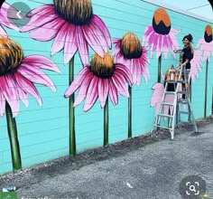 a man is painting a mural on the side of a building with flowers painted on it