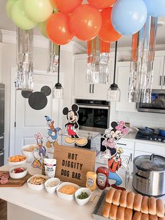 a mickey mouse themed birthday party with balloons and food on the counter in front of it