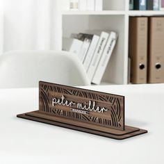 a wooden business card holder sitting on top of a white desk next to bookshelves