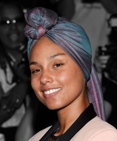 a woman wearing a turban and smiling for the camera with people in the background